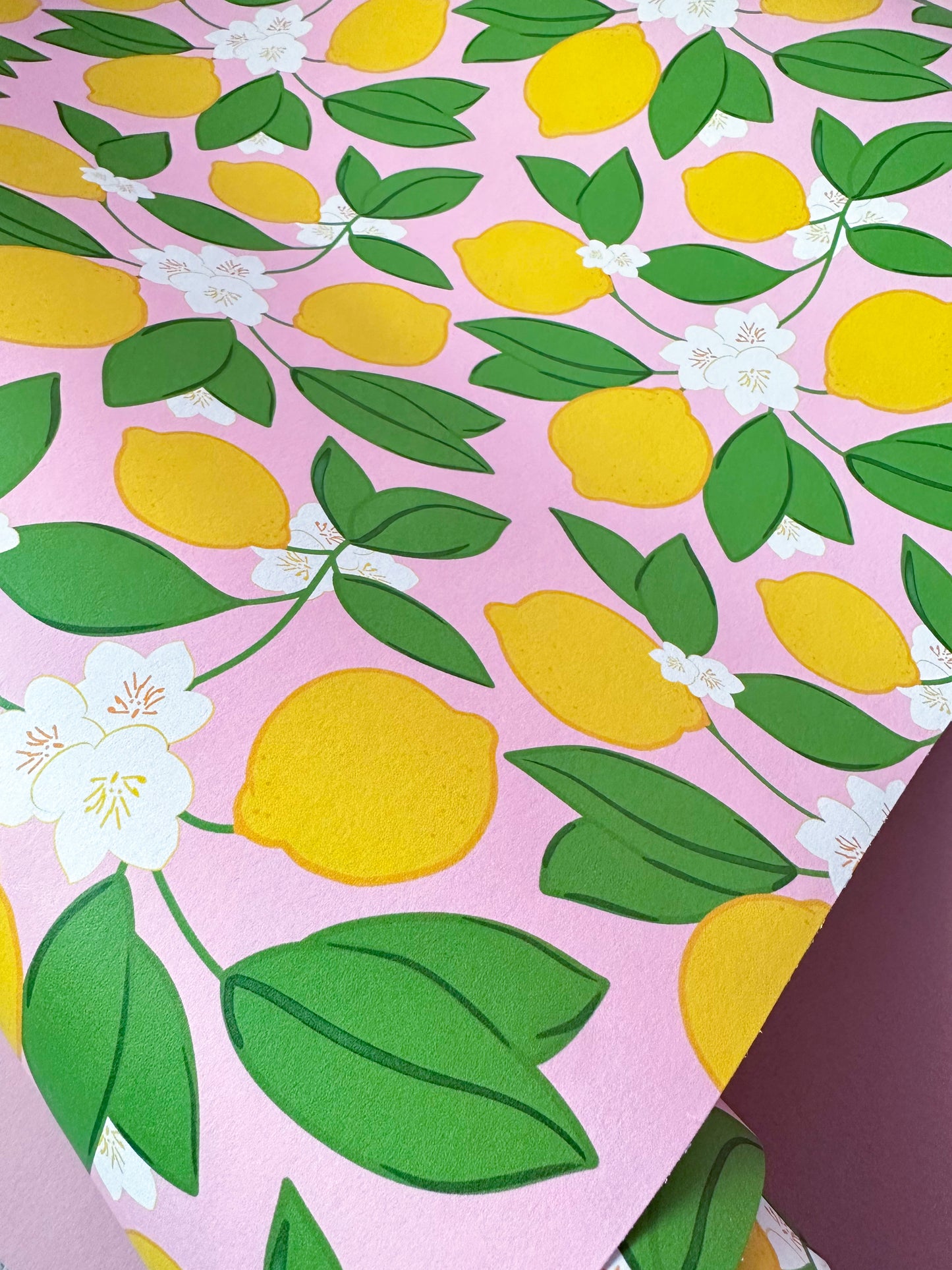 wallpaper with lemons, green leaves, and white flowers on a pink background