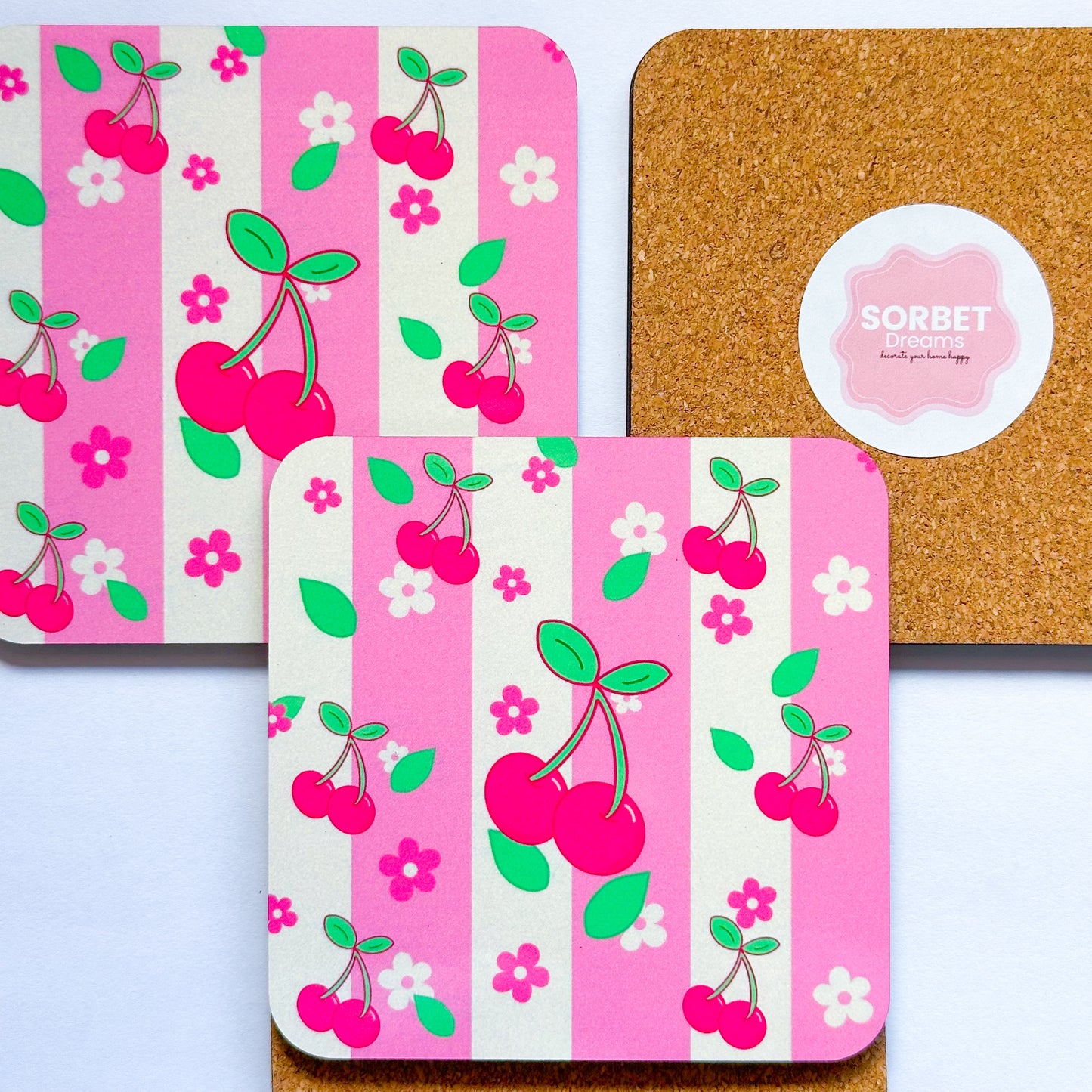 Set of coasters with cherry design on pink and white striped background, featuring a cork backer.