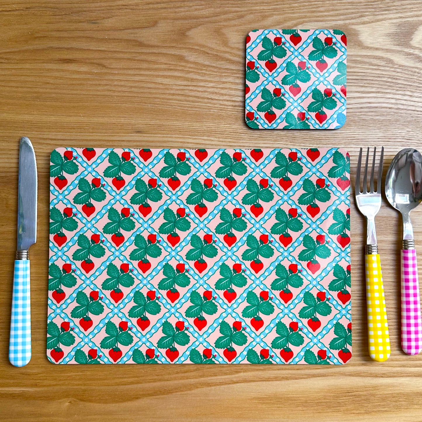 Placemat and coaster set with strawberry pattern on a wooden surface