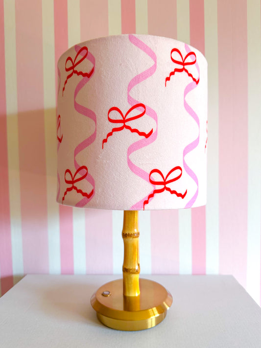 Decorative lampshade featuring red bows and pink ribbons 