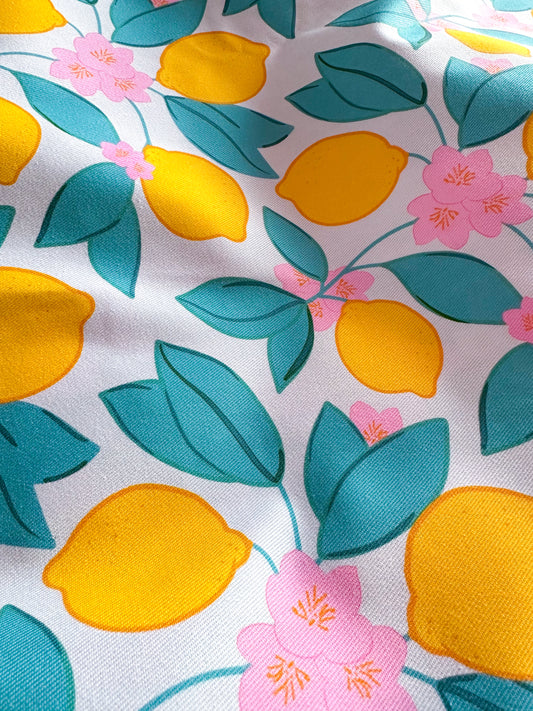 Fabric with yellow lemons, pink flowers, and blue leaves on a white background
