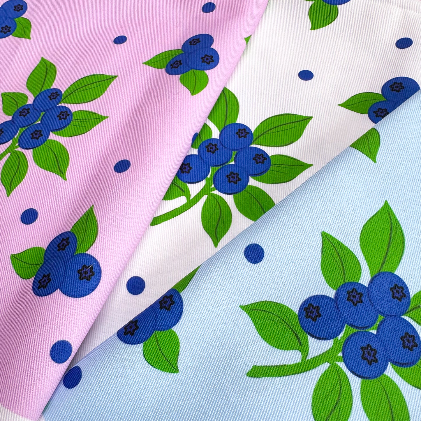 Fabric swatches with blueberry pattern on pink, white, and light blue backgrounds
